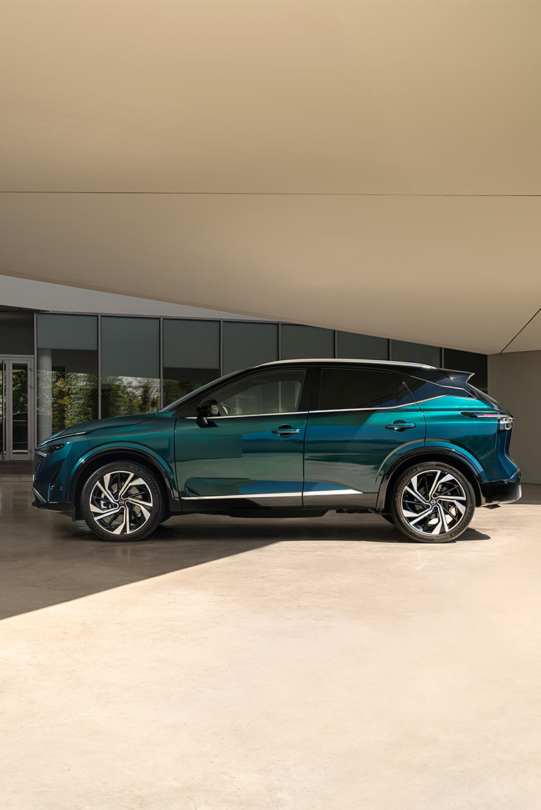 Imagen lateral del Qashqai e-Power bajo un techo cubierto, destacando llantas deportivas y líneas de diseño elegantes