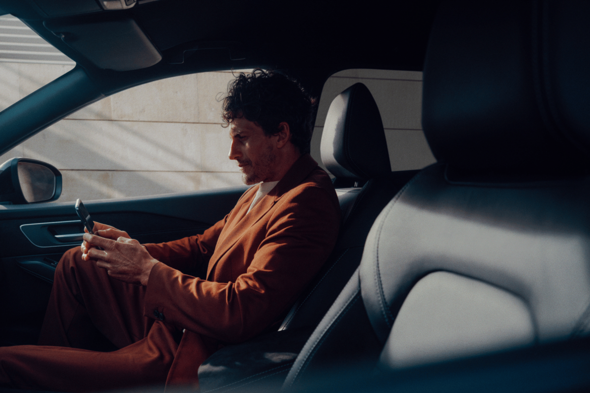 Vista lateral de un hombre usando la aplicación del sistema NissanConnect en su smartphone