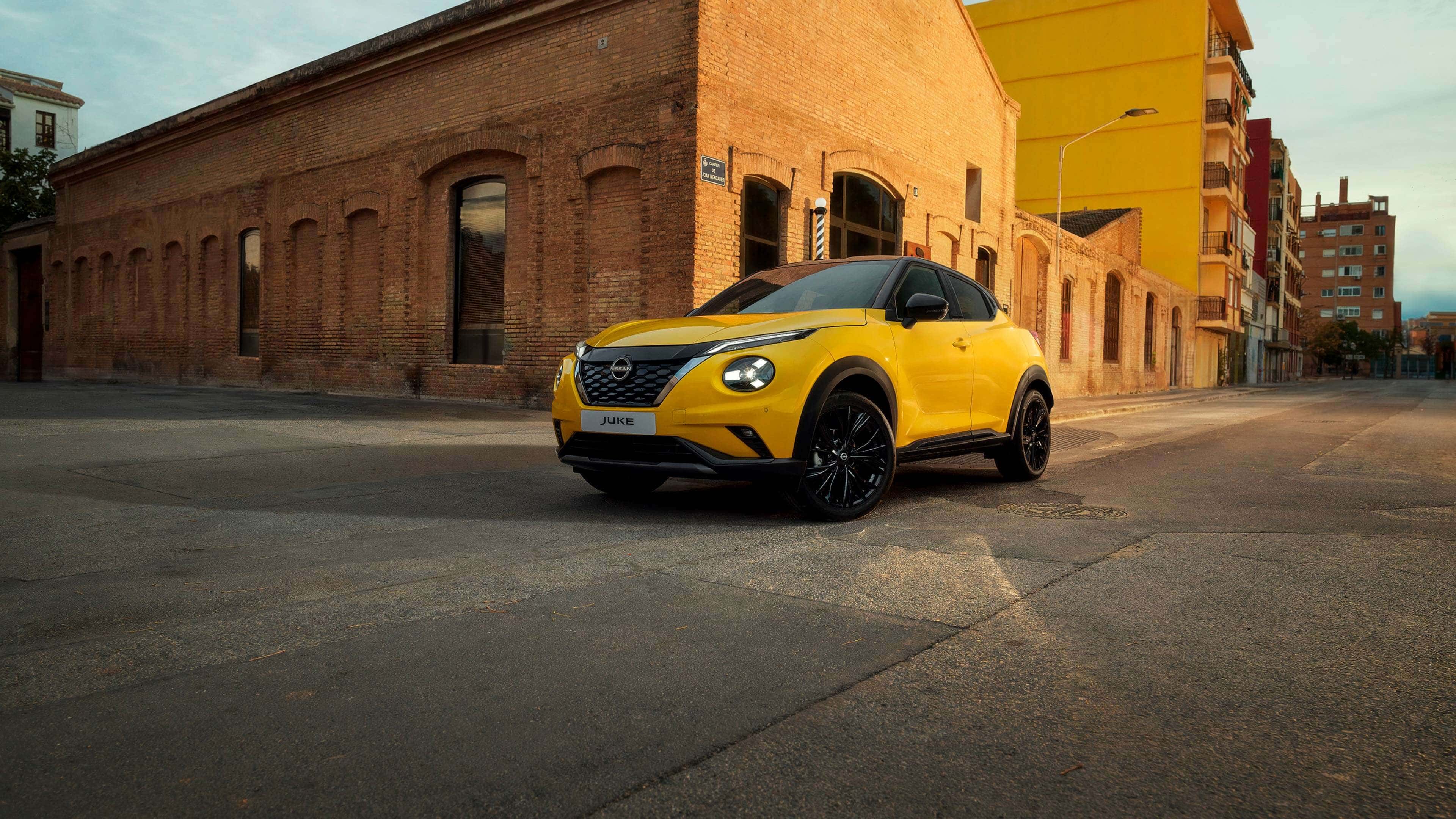 Vista estática delantera 3/4 del Nissan Juke delante de un antiguo almacén