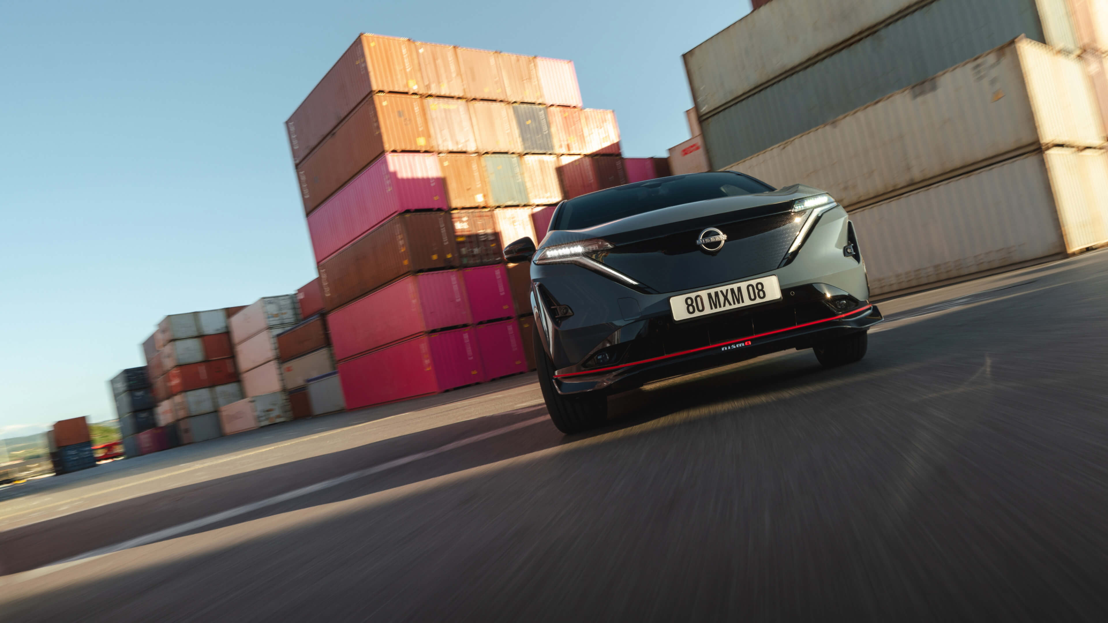 Nissan ARIYA NISMO en movimiento junto a unos contendores