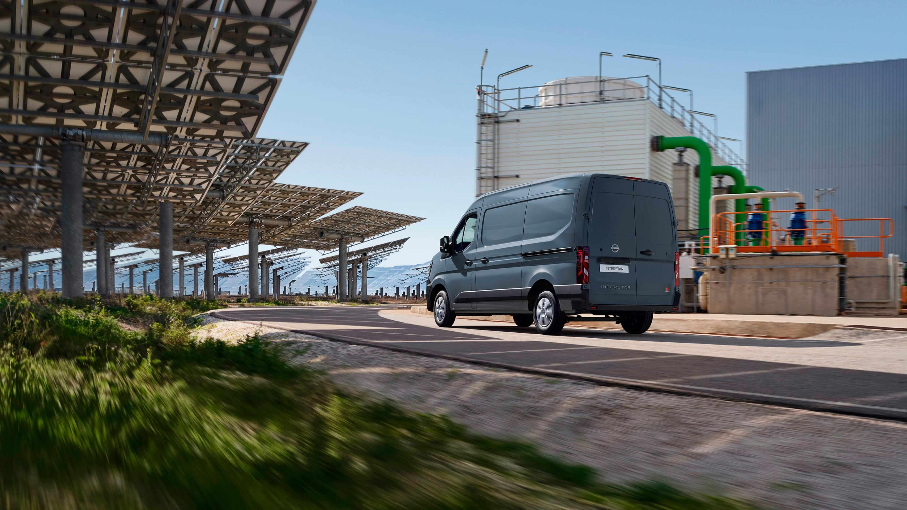 Furgoneta Nissan INTERSTAR diésel y eléctrica aparcada frente a paneles solares