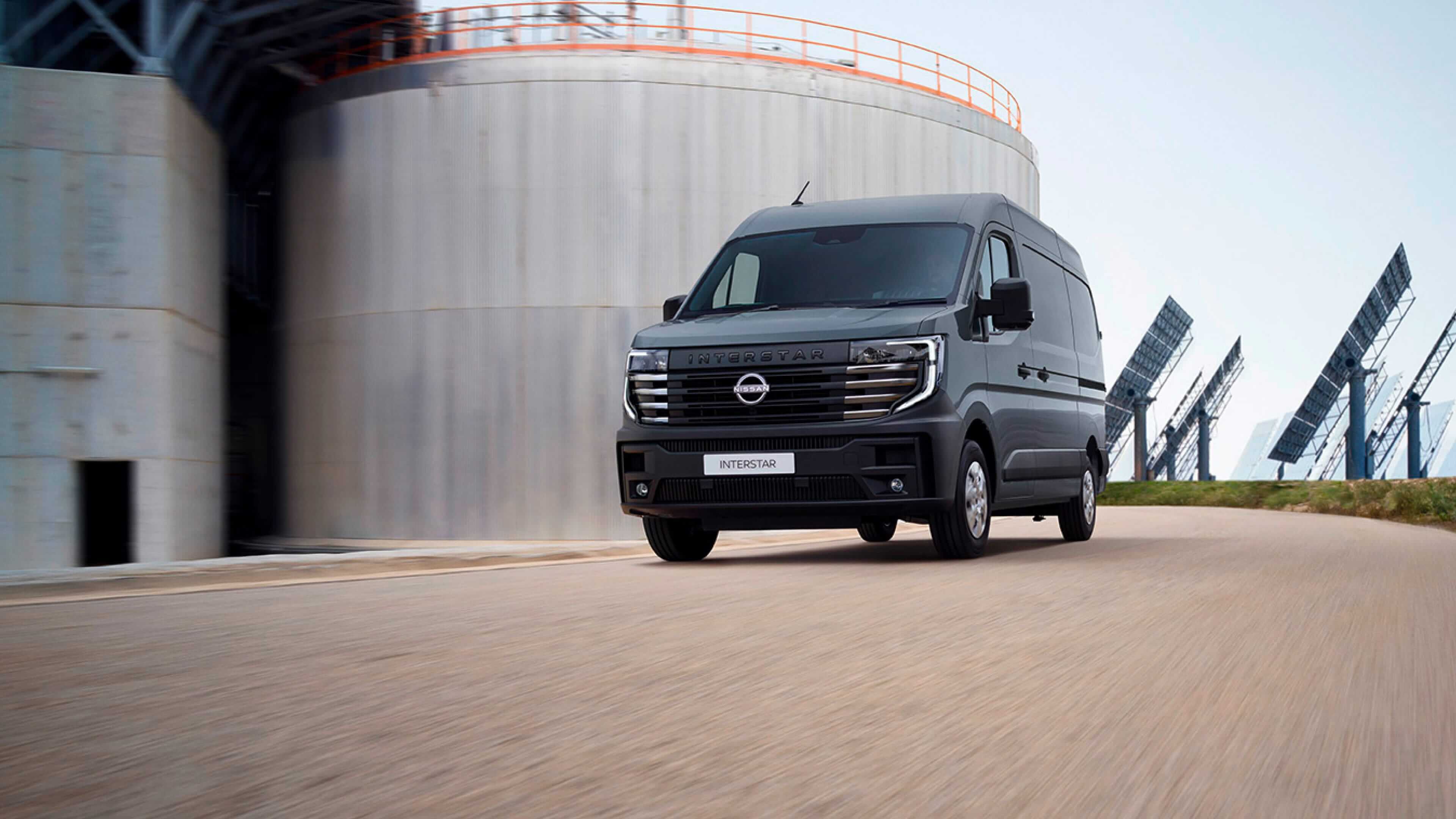 Furgoneta Nissan INTERSTAR diésel y eléctrica aparcada frente a paneles solares