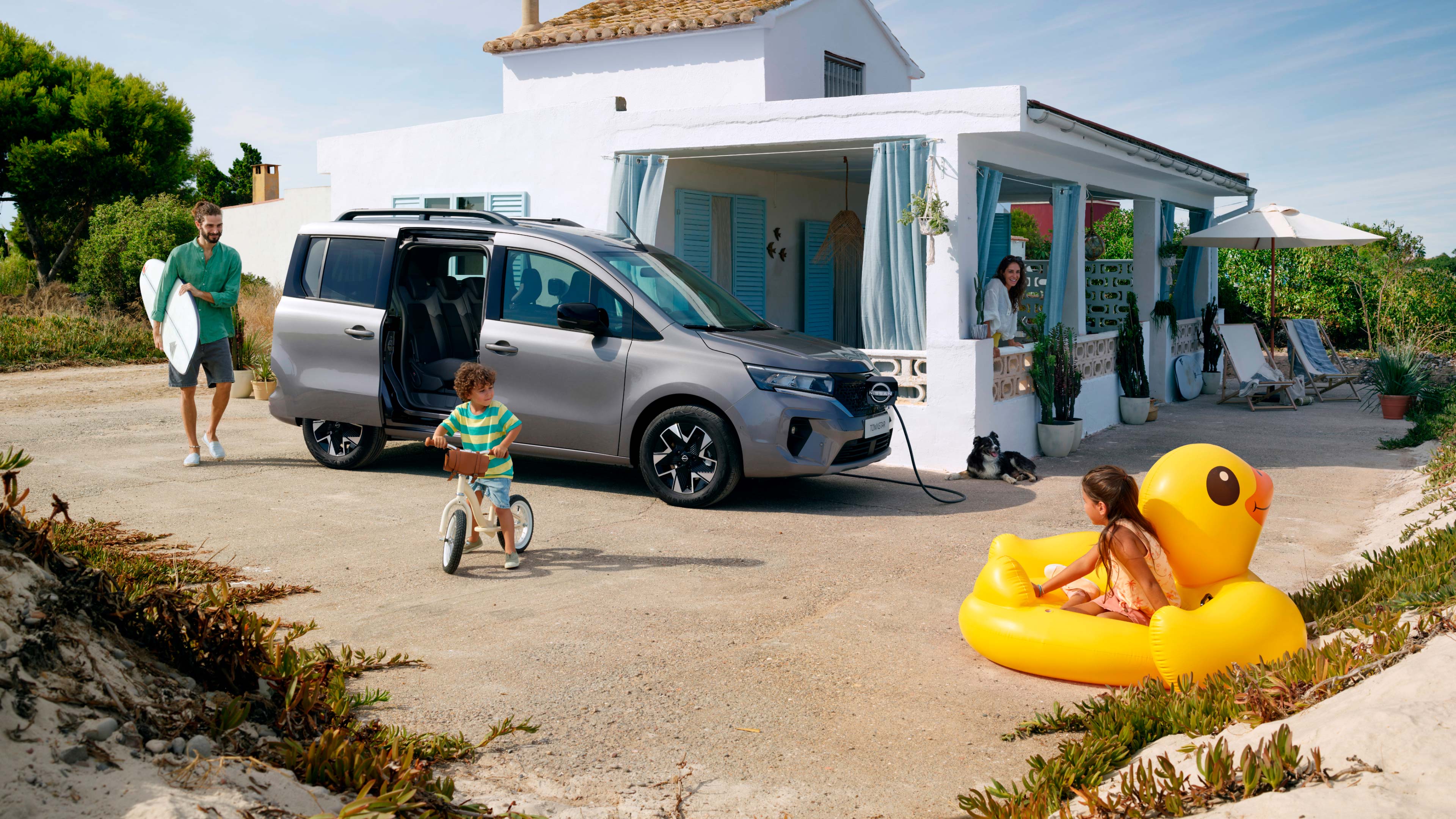 Nissan towsntar Combi gris con una Familia en una casa de la playa