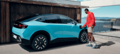 " Un homme branche sa voiture sur une borne de recharge domestique. "