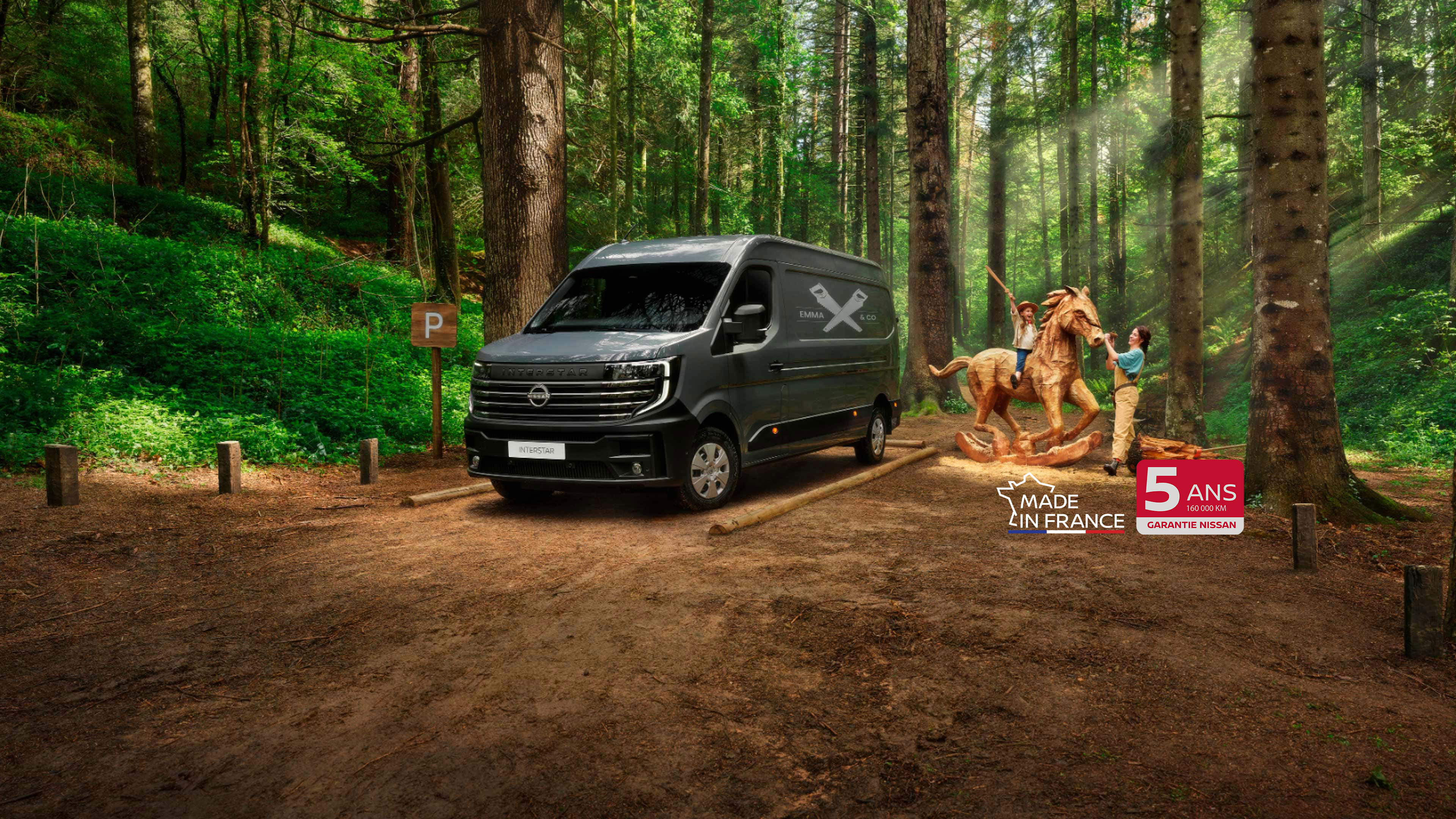 Nissan INTERSTAR fourgon 3/4 face stationné dans une forêt et famille jouant autour d’un cheval de bois  