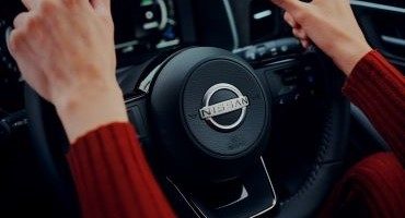 Two men servicing a red Nissan car