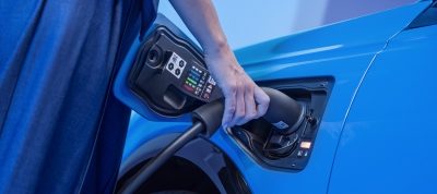 A man plugs his car into a home-charging unit.