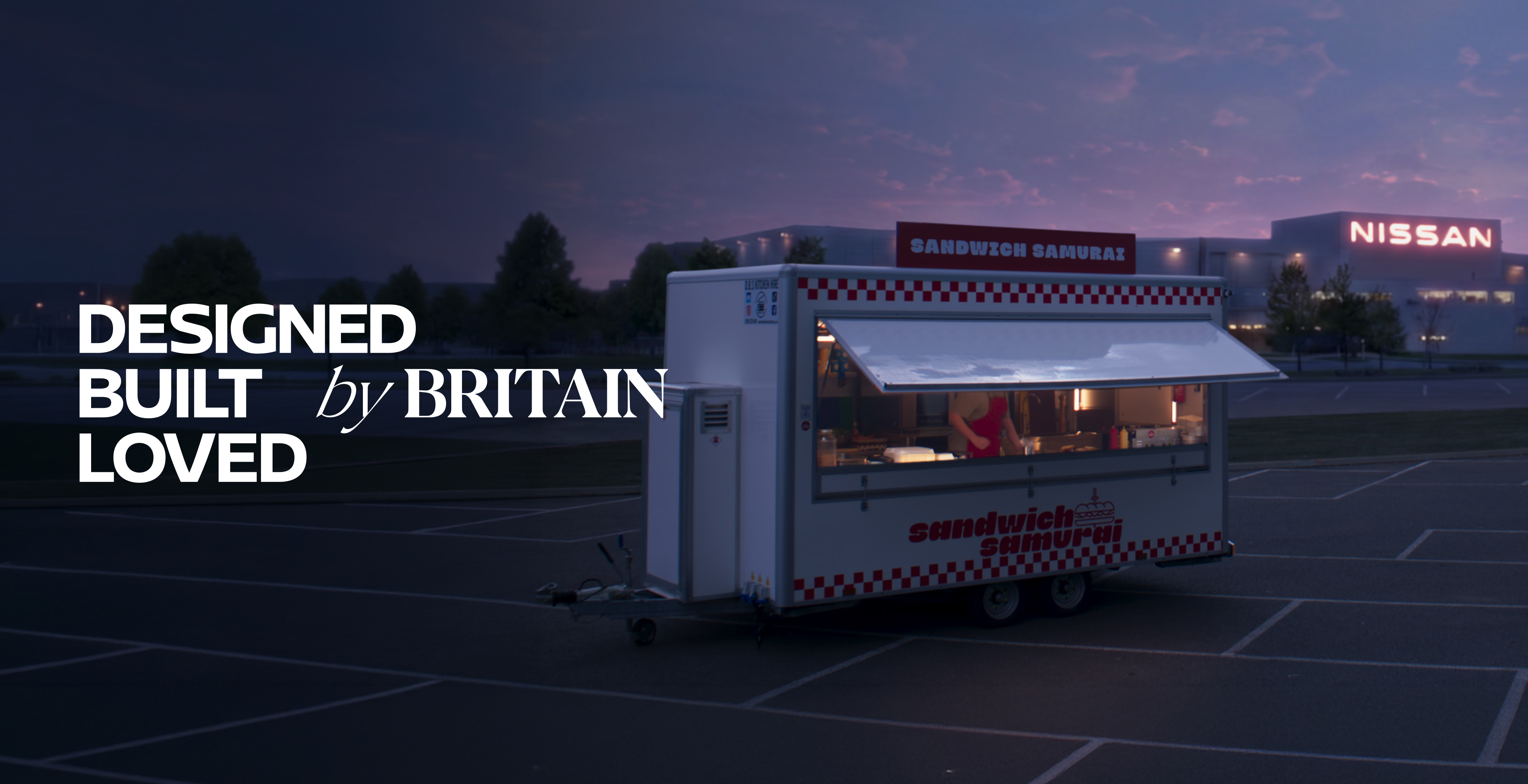 Sandwich stand in front of a Nissan factory at dusk with text reading 
