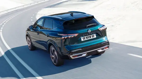 A blue nissan Qashqai lifted in a service centre with two technicians working on the undercarriage