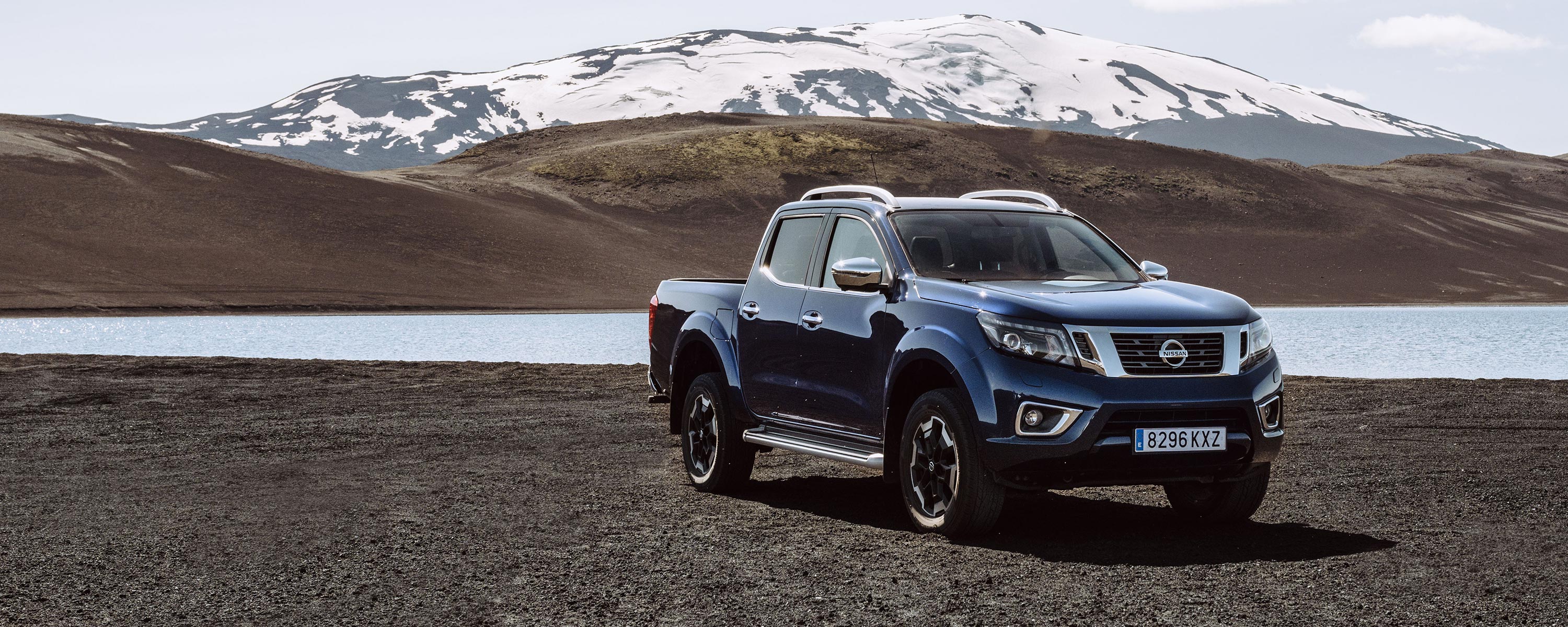 Nissan Navara au bord d'un lac sur fond de sommet enneigé