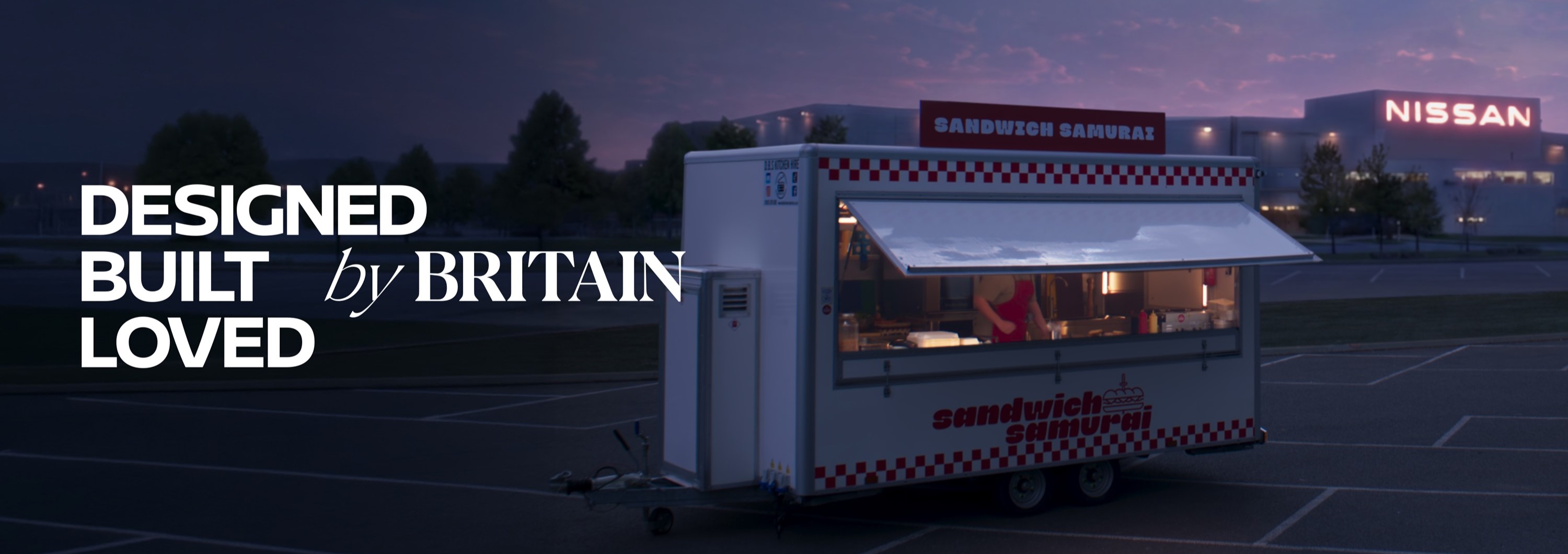 Sandwich stand in front of a Nissan factory at dusk with text reading 