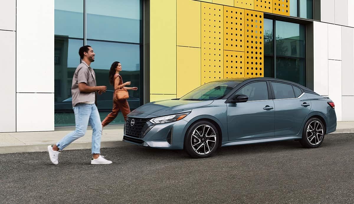 גבר ואישה לצד רכב ניסאן סנטרה ברחוב עירוני