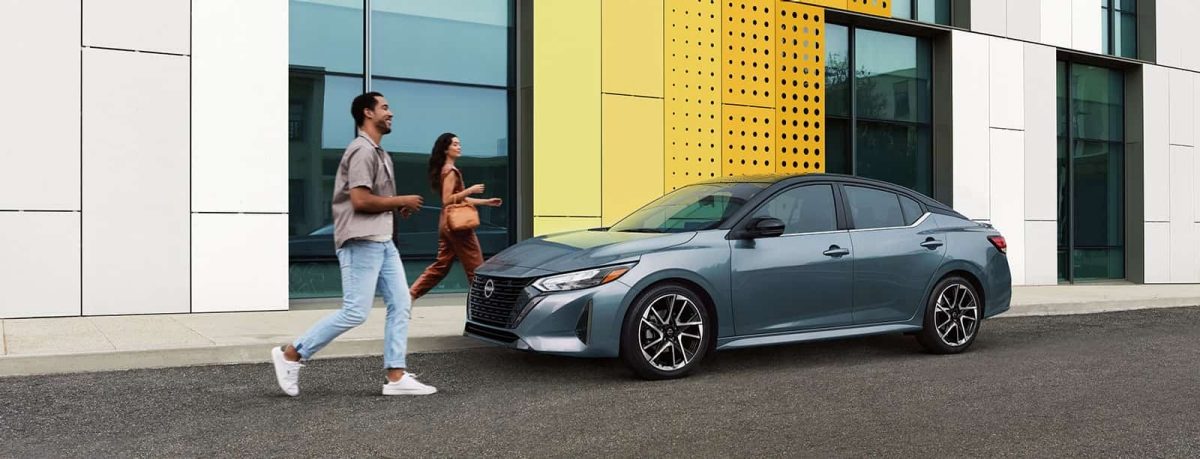 גבר ואישה לצד רכב ניסאן סנטרה ברחוב עירוני