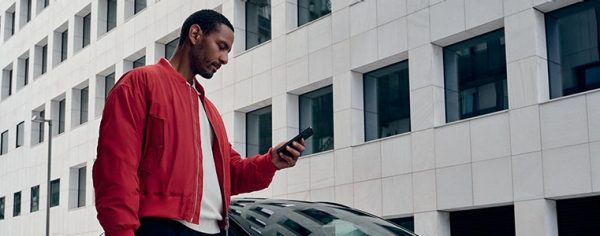 Una mano che regge uno smartphone, che mostra l’app NissanConnect Services.