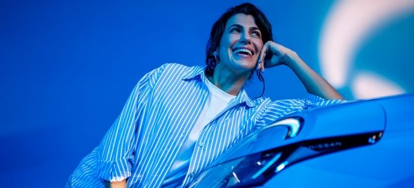 Donna sorridente appoggiata al cofano di una Nissan Micra