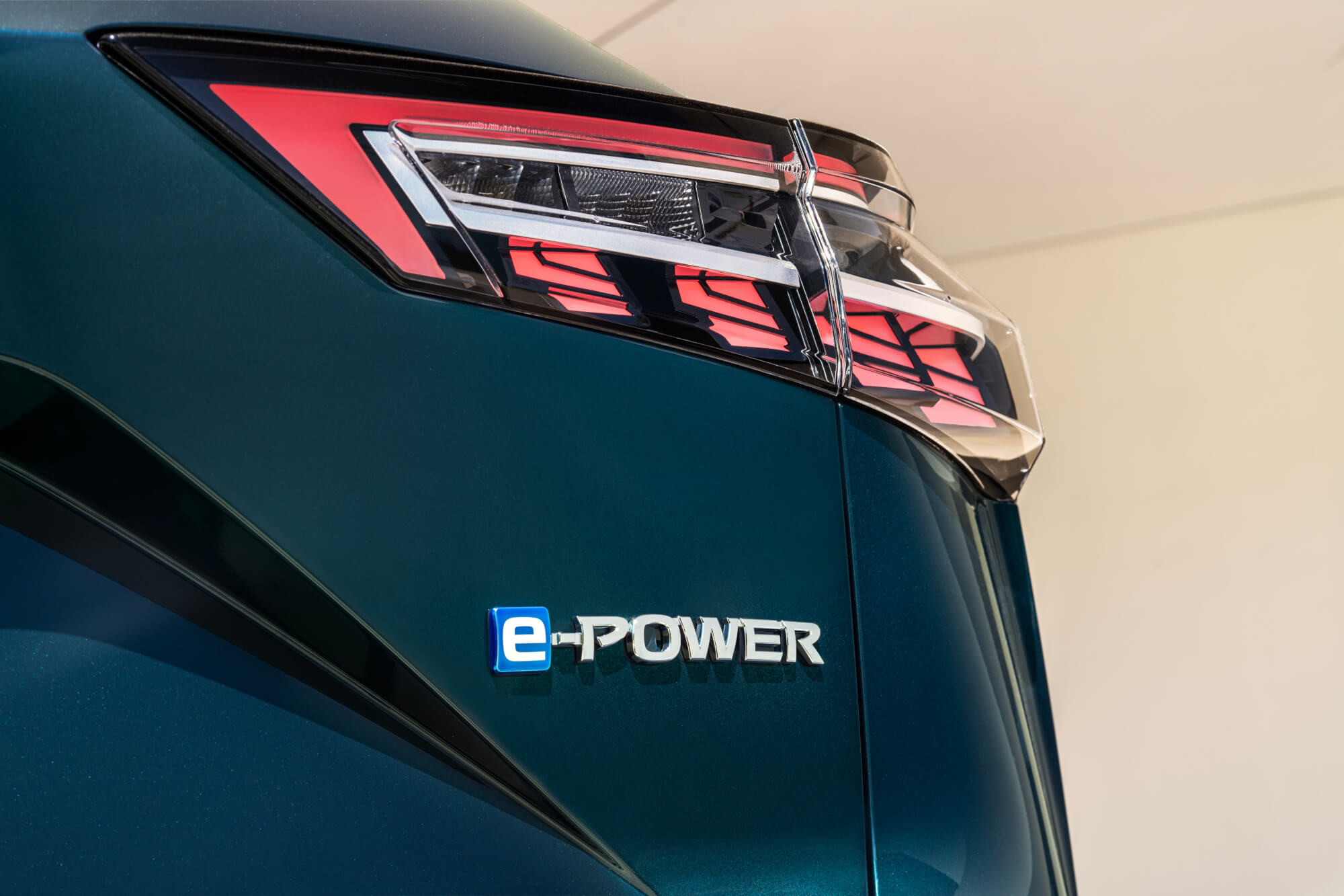 Nissan Qashqai e-POWER, braucot pa ielu ar tiltu fonā – SUV hibrīds.