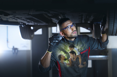 Nissan mehāniķis pārbauda automobili uz pacēlāja.