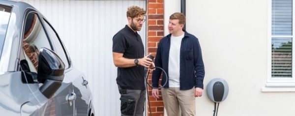 Moteris įkrauna automobilį per buitinį įkroviklį.