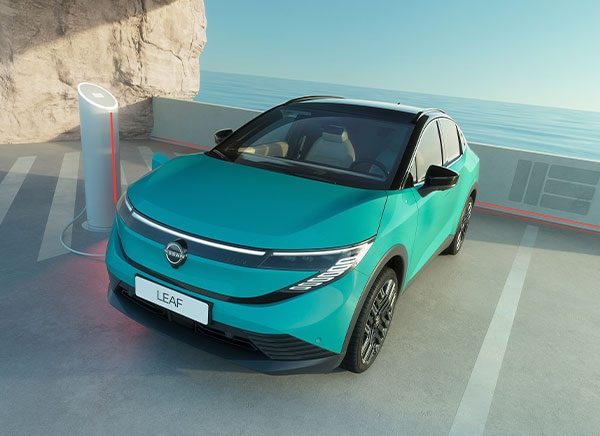 Nuevo Nissan LEAF cargándose en exterior con mar de fondo.