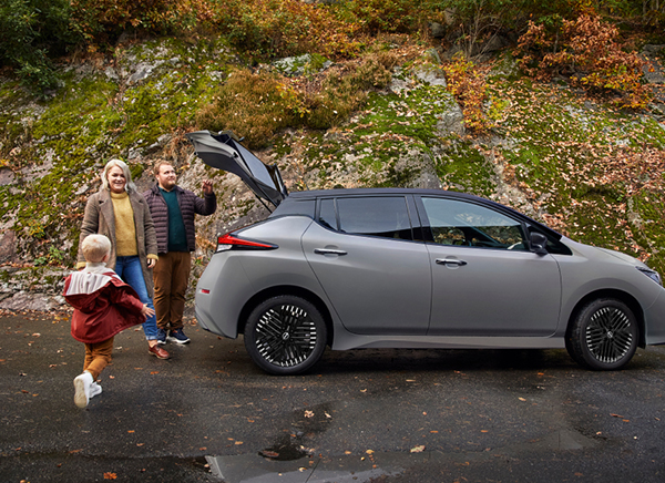Grå Nissan LEAF og en familie med små barn som står rundt elbilen