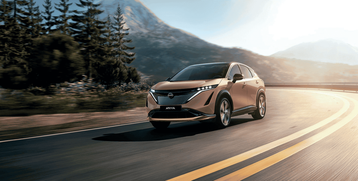 Nissan ARIYA set oppefra i idyllisk landskab, mens den tager et sving
