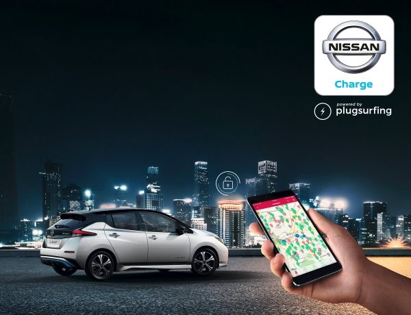Mão a segurar um Smartphone com o ecrã da Nissan Charge com o Nissan LEAF estacionado com uma cidade no fundo e o logótipo de aplicação