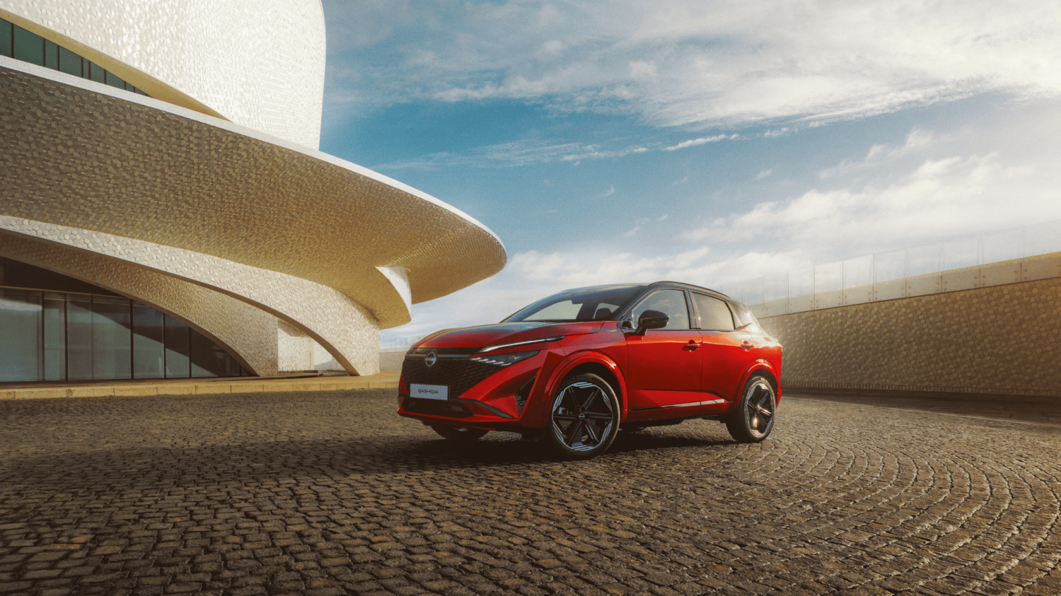 Nissan Qashqai e-Power etukulmasta nähtynä rakennuksen edessä nuoren parin kävellessä auton ympärillä – hybridikatumaasturi