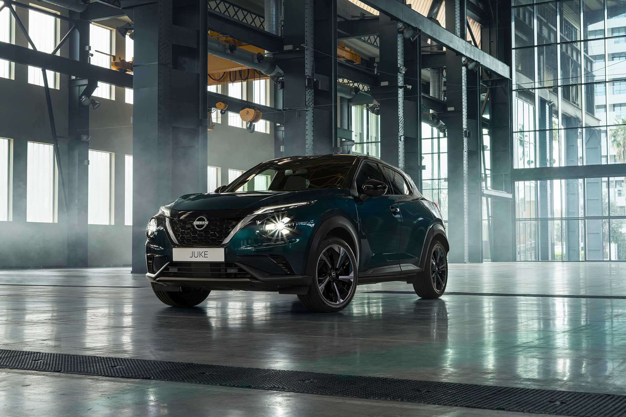 3/4 statisk vy framifrån av Nissan JUKE Hybrid SUV framför lagerlokal