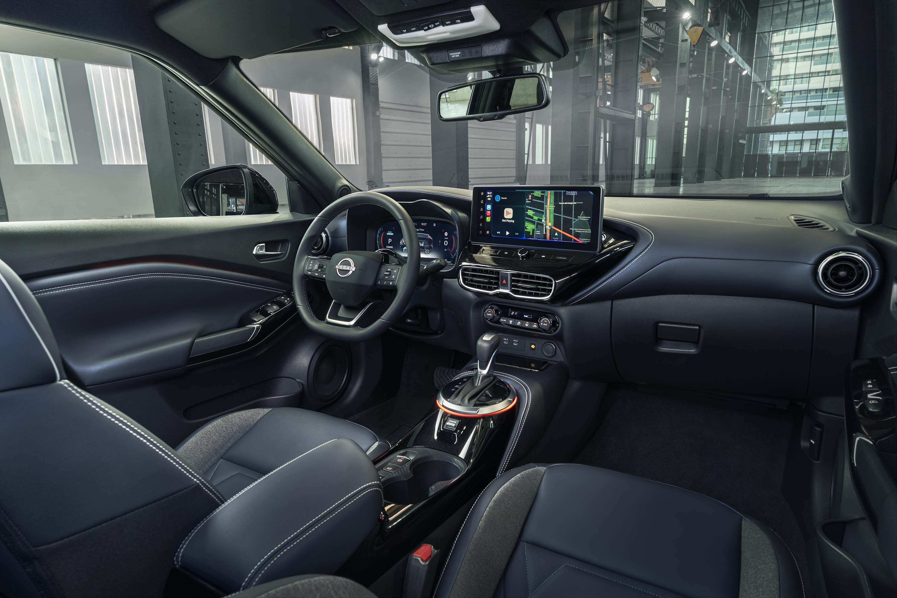 Interiör vy framifrån av instrumentpanelen i Nissan JUKE Hybrid SUV med passagerare