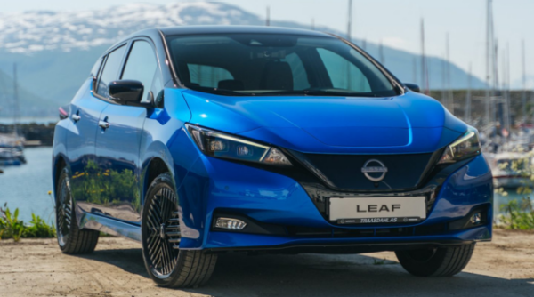 Bilde av blå Nissan LEAF elbil parkert på en brygge med seilbåter og fjell i bakgrunnen