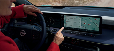 Notranjost Nissan vozila z digitalnim armaturnim zaslonom in navigacijo na dotik med vožnjo.