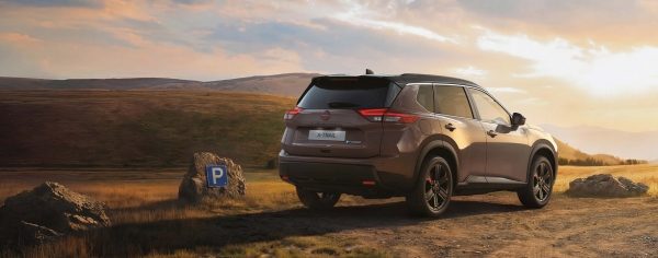 Nissan X-Trail, sivo vozilo, stražnji pogled u prirodi na makadamu pri zalasku sunca