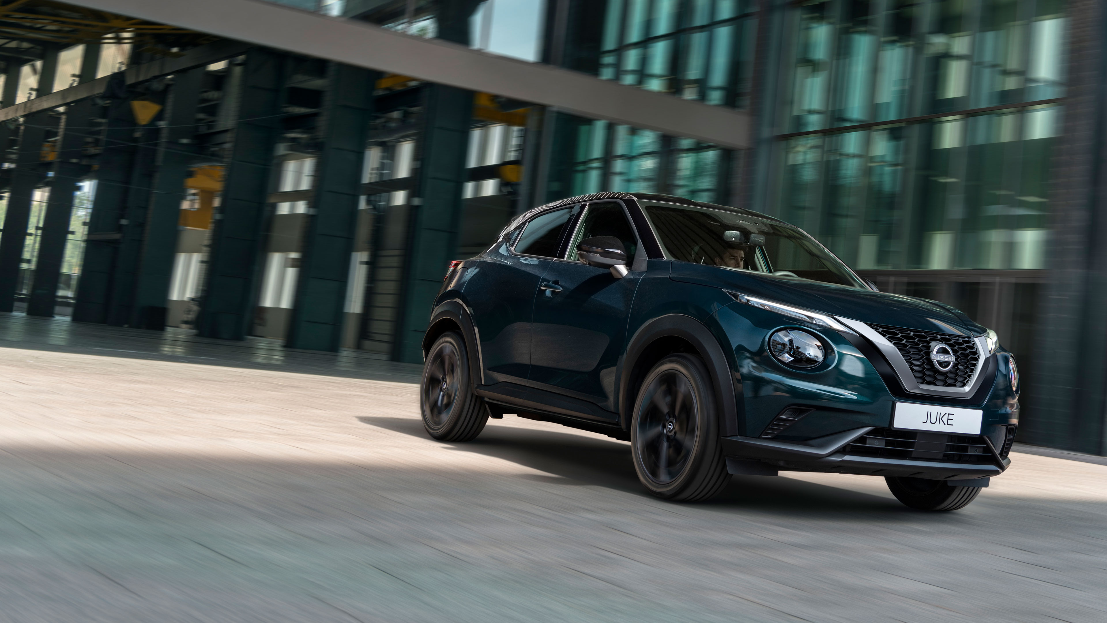 Зображення Nissan JUKE, який стоїть перед складським приміщенням, вид спереду 3/4